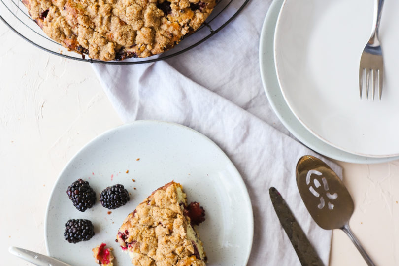 Slice of Blackberry Cake on a gray plate with a fork on a white background