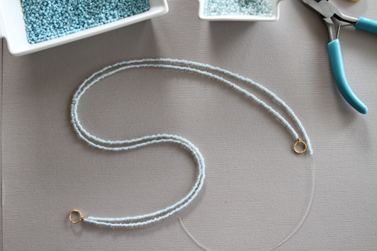 two strings of light blue beads with two gold jump rings