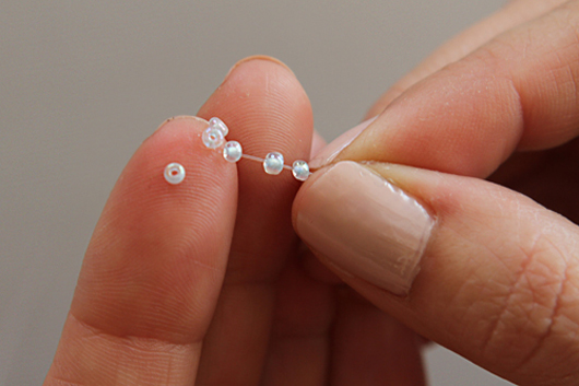 threading the first beads on the necklace string