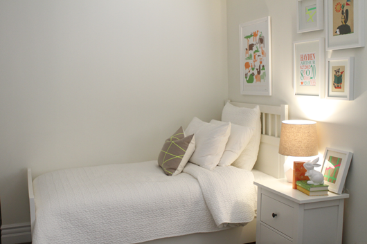 white bed and night stand with colorful photos on the wall