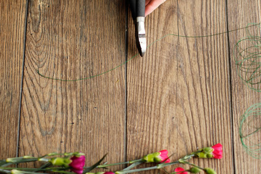 woman cutting green florist wire on wood table