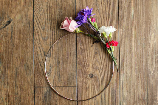 pink roses and purple and white carnations attached to a metal hoop