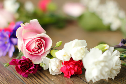 pile of pink roses, and carnations against a wood table