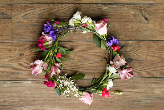 metal hoop adorned with various spring flowers sitting on a wood table