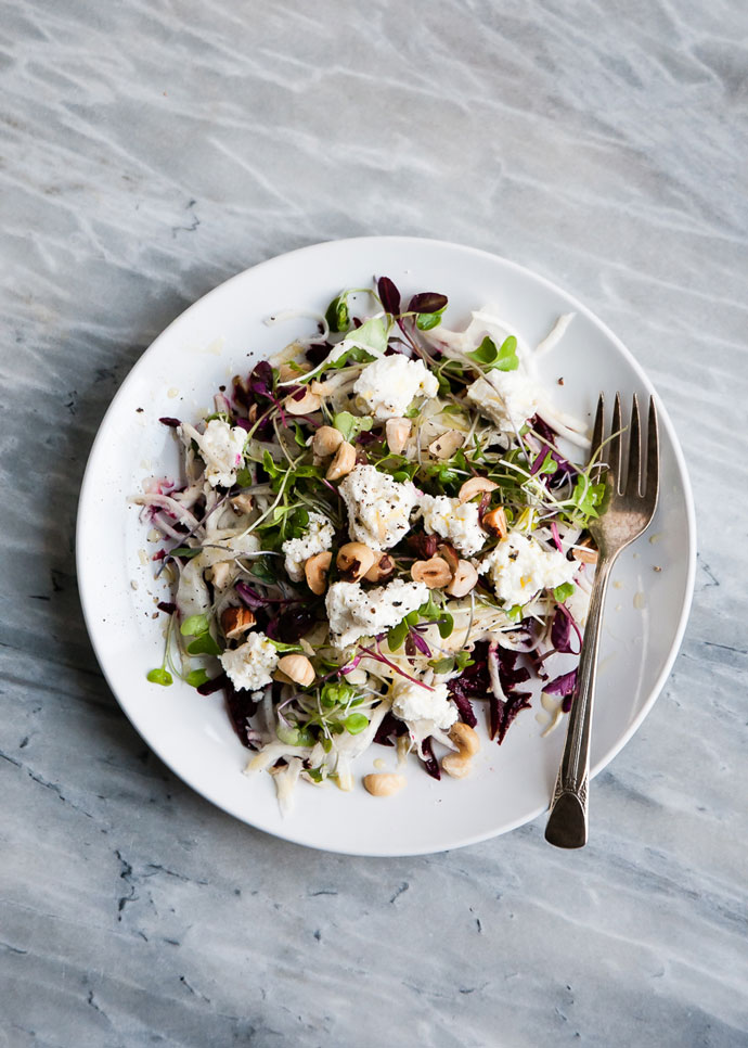 Early spring salad on a white plate topped with hazelnuts and goat cheese