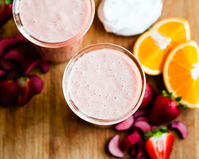 2 glasses filled with strawberry dairy free smoothie, with orange slices 