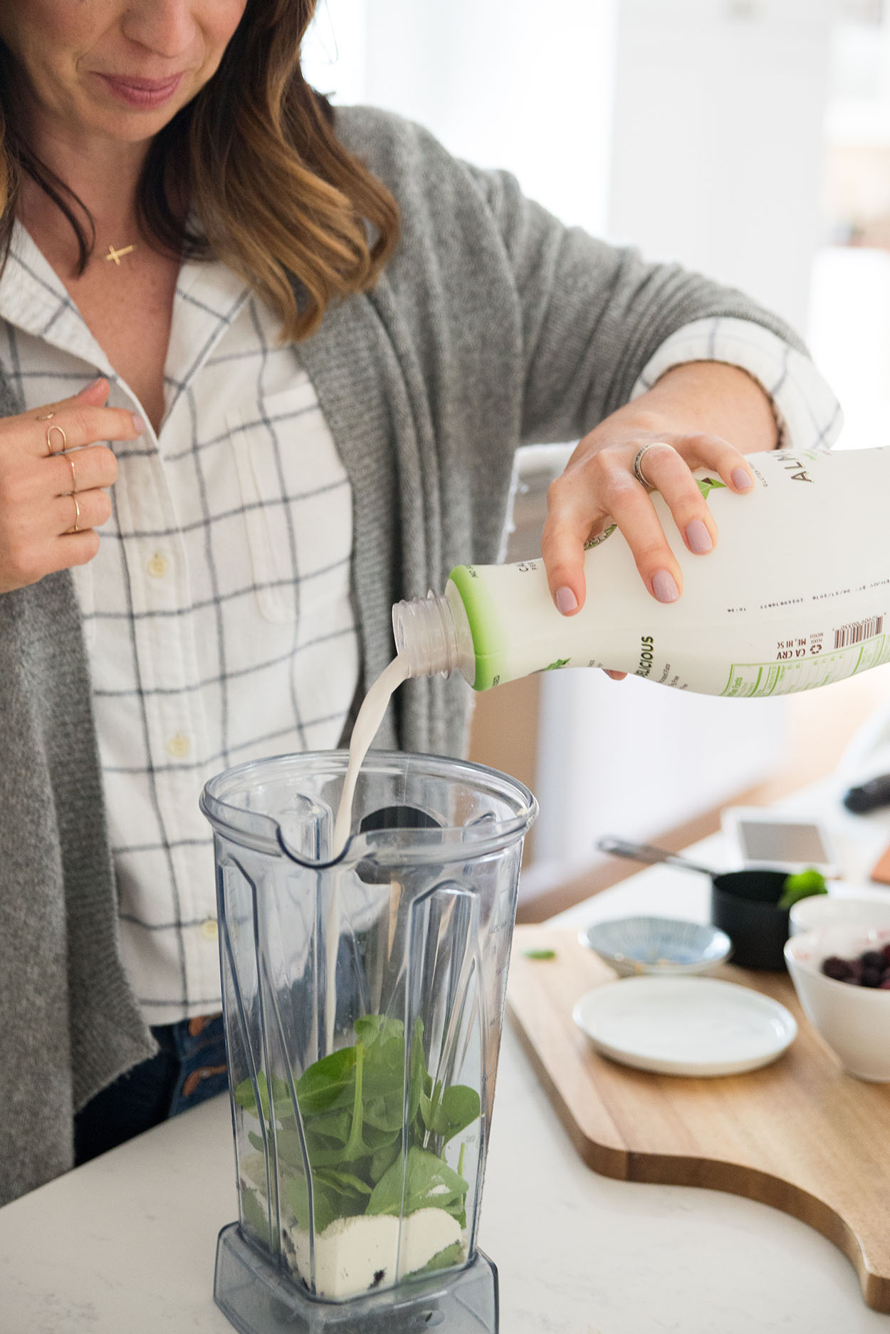 woman pouring almond milk into a blender