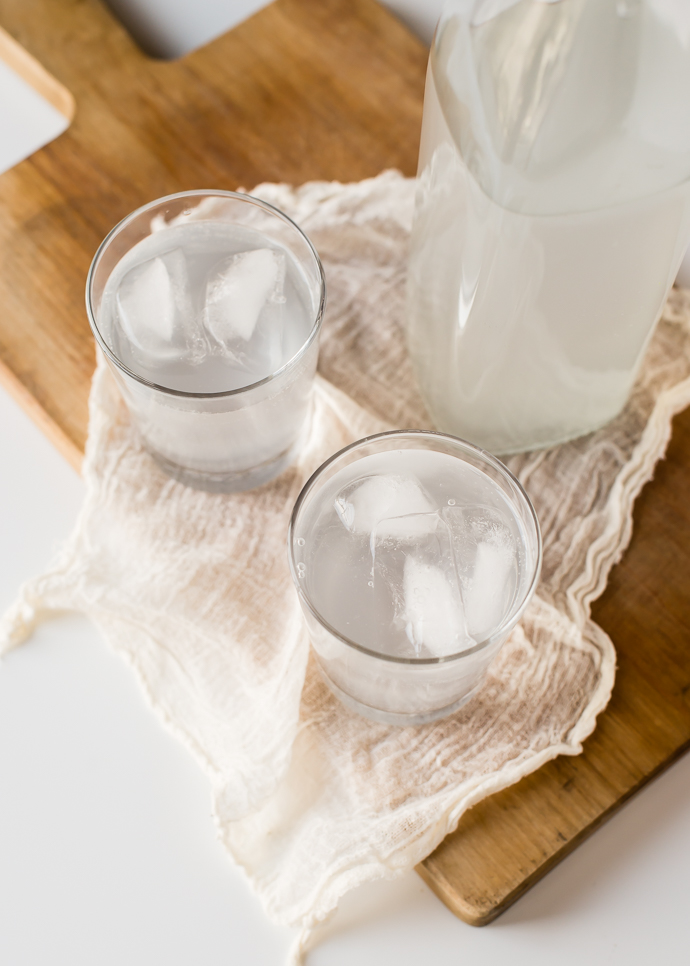 bubbly kefir water in two glasses with ice sitting on a cutting board