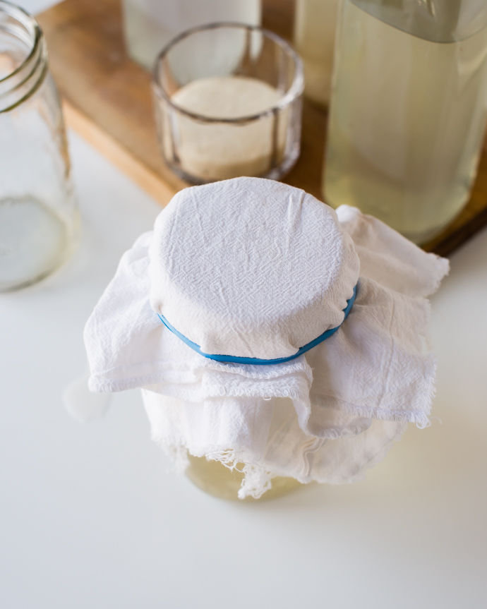 a glass mason jar covered in a white cloth 