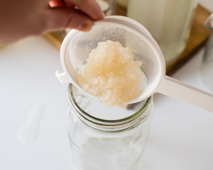 using water kefir grains being poured into a glass jar