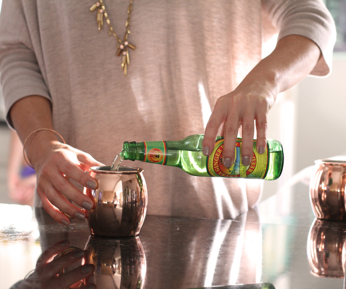 pouring ginger beer into a copper mug for an apple cider moscow mule