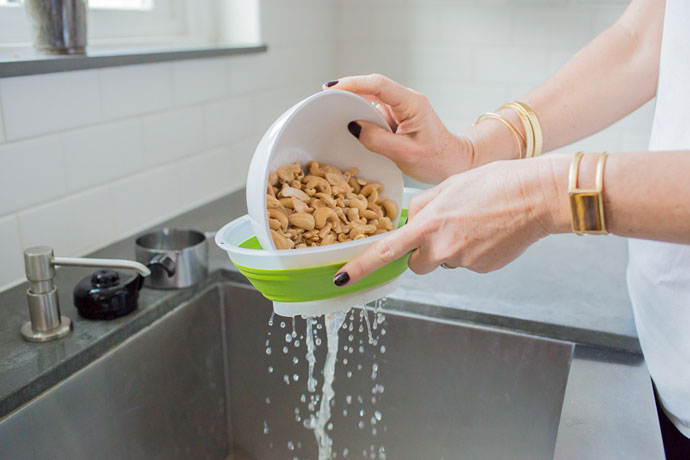 straining water out of bowl filled with cashews 