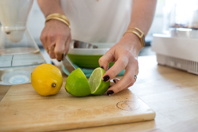 cutting a lime in half on a wooden cutting board