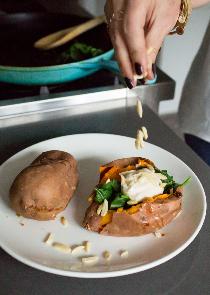 woman sprinkling slivered almonds on a sweet potato