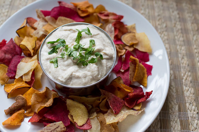 cashew cream sauce in a silver container surrounded by chips