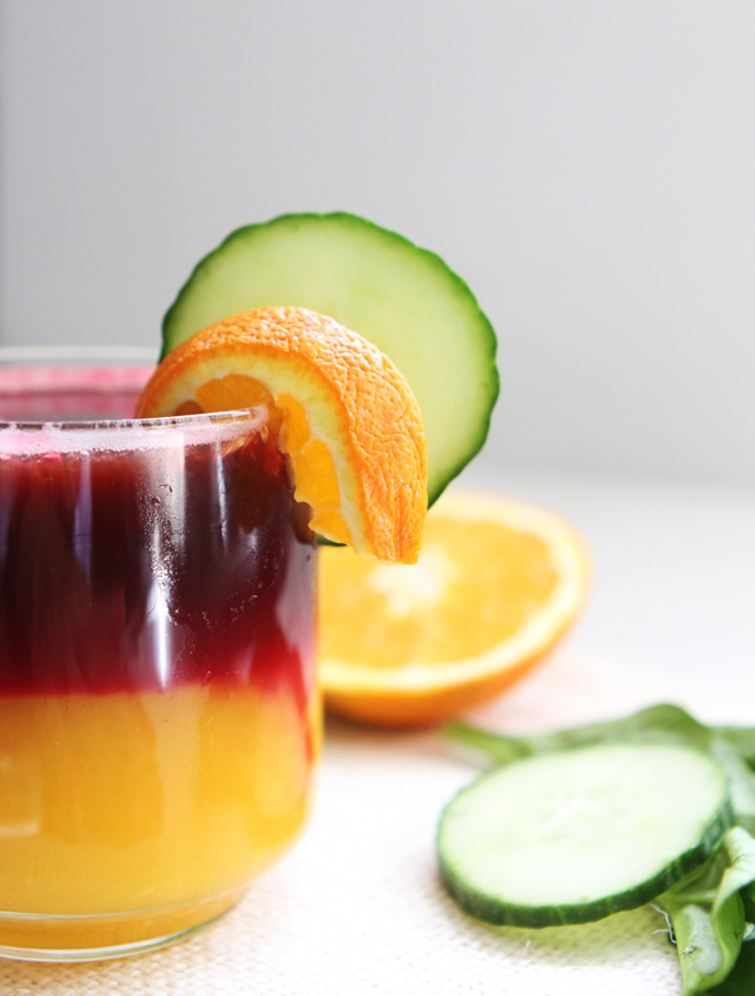 rim of rainbow juice glass garnished with orange and cucumber slices