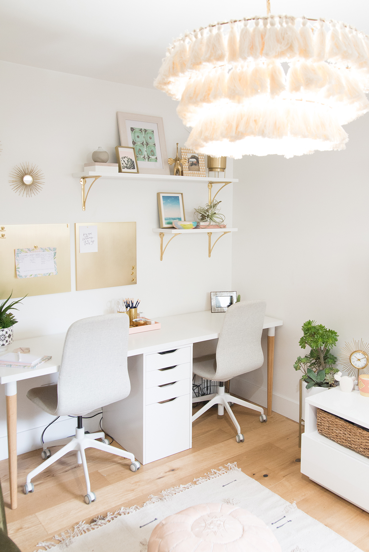 office space with a white desk and two gray chairs, a chandelier with pink tassels