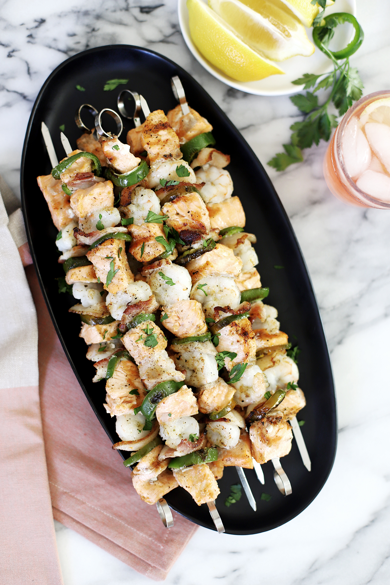 overhead picture of shrimp and salmon skewers on a black plate 