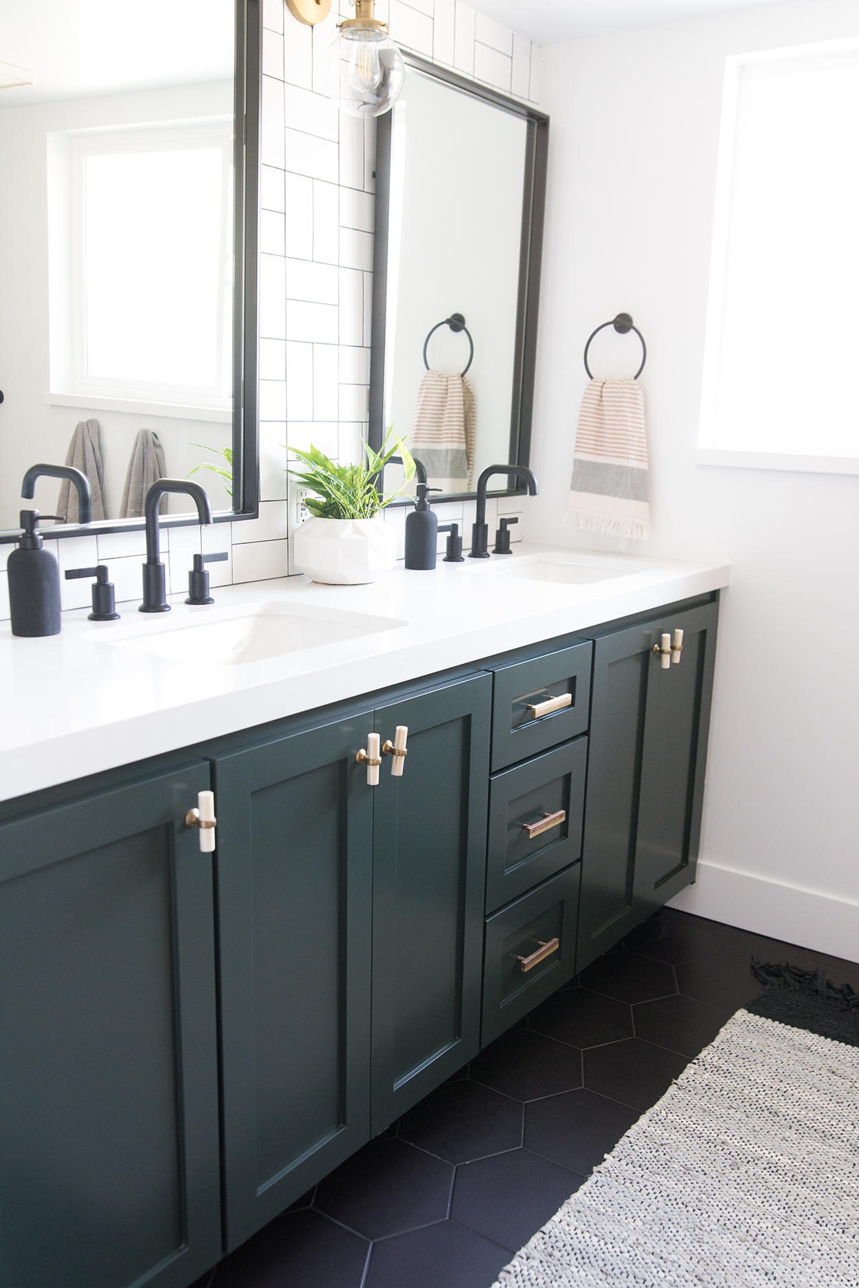 A black bathroom vanity with a white coutertop and black fixtures