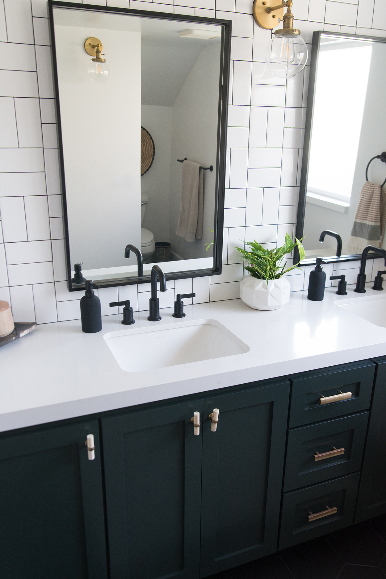 white and black tiled bathroom wall with a black mirrors and a black vanity with a white counter