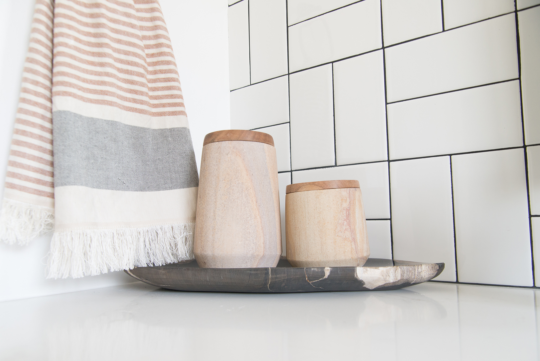 white tiled wall, a towel hanging and a cup and toothbrush holder