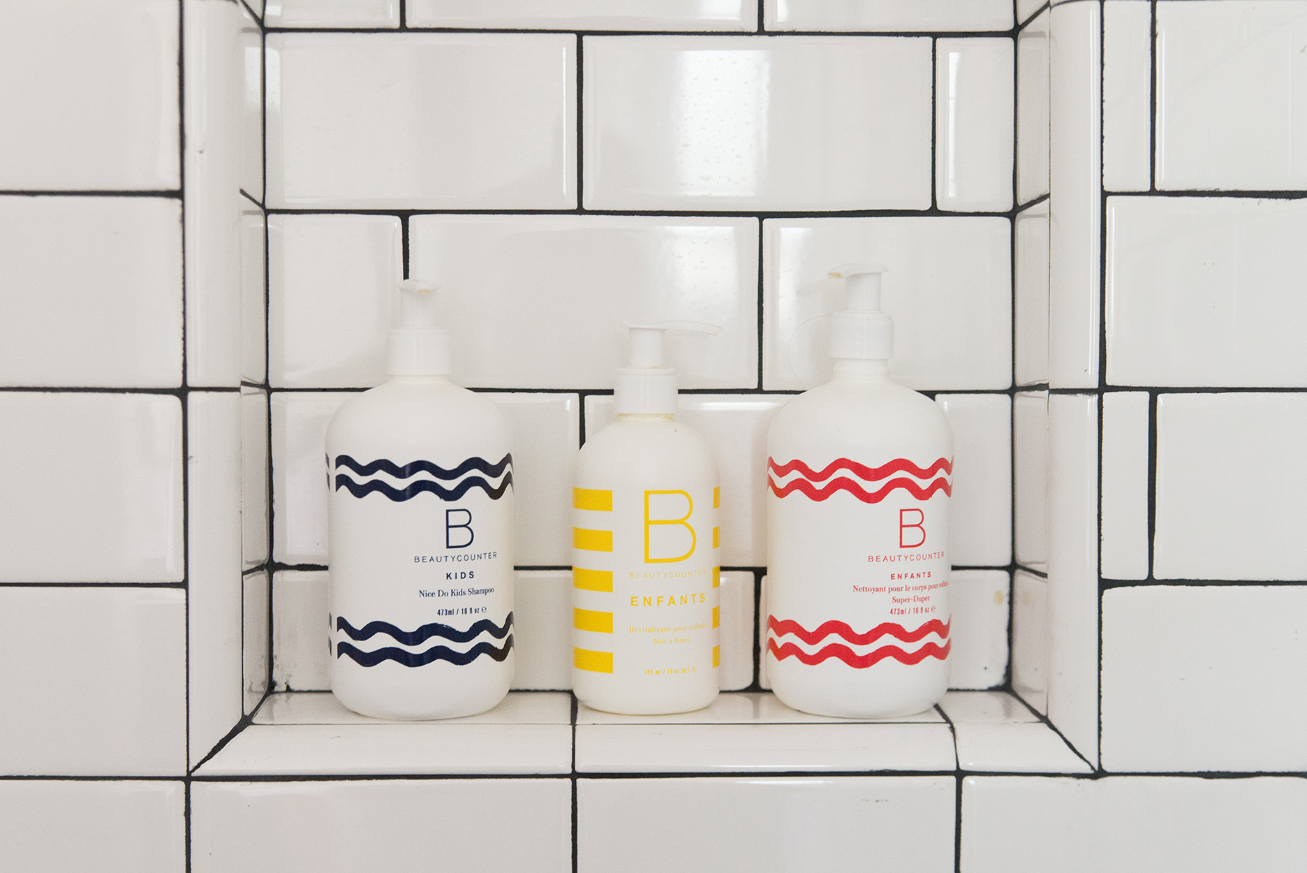 beauty counter shampoo and body soap in a white tiled shower