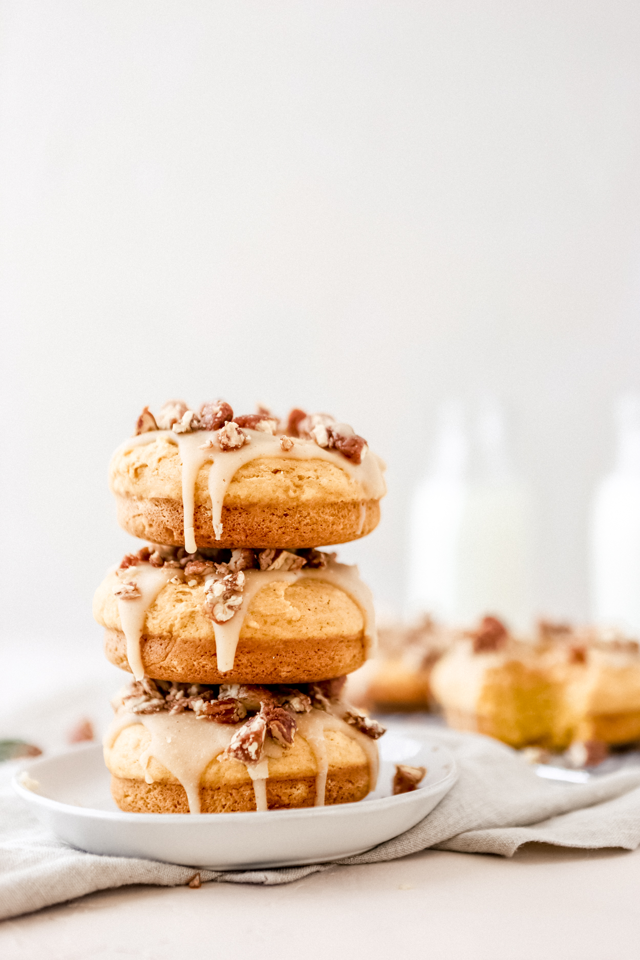 a stack of three baked pumpkin donuts on a white plate