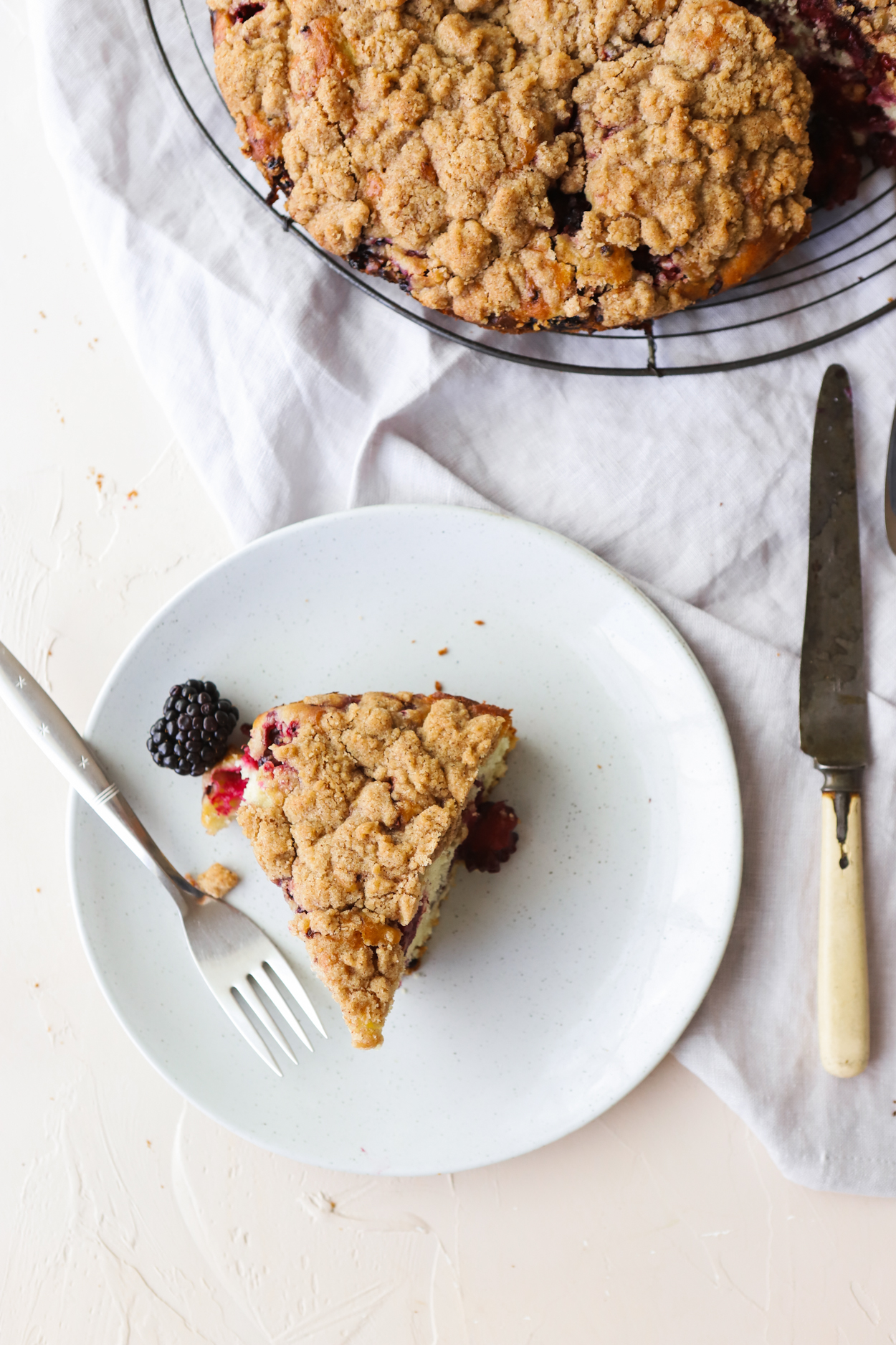 Slice of Blackberry Cake on a gray plate with a fork on a white background 