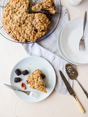 Slice of Blackberry Cake on a gray plate with a fork on a white background