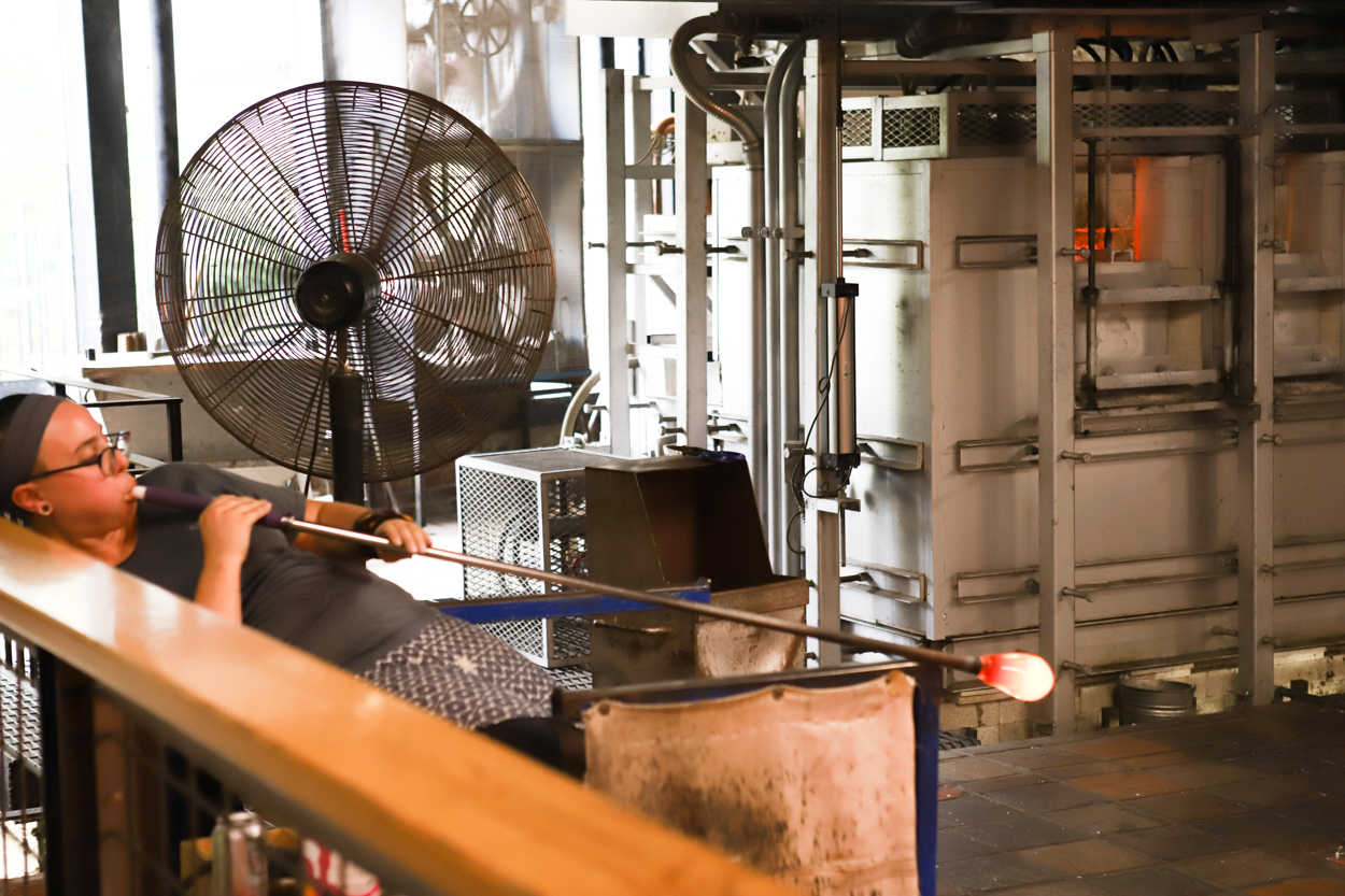 Woman blowing glass at Simon Pearce gallery in studio in Quechee Vermont 