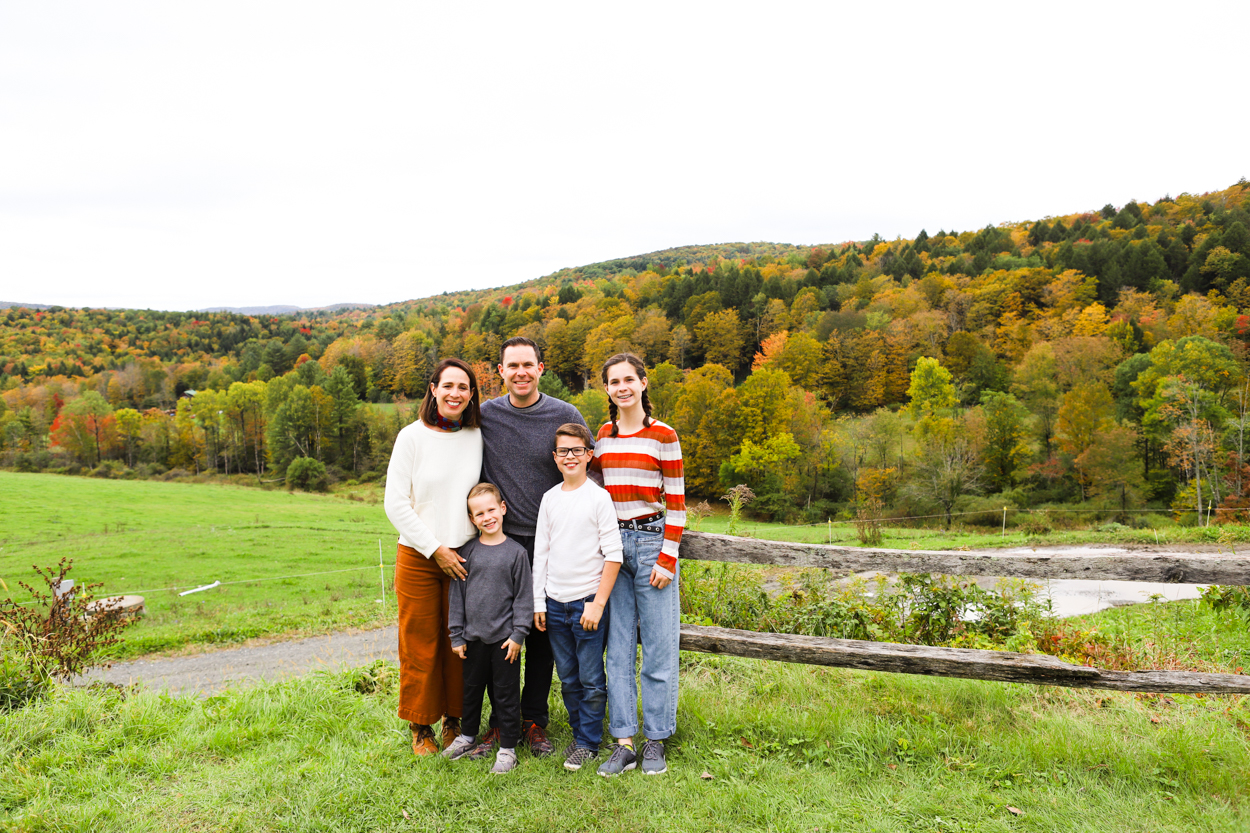 Family standing in front of Green Mountains at Sugarbush Farm in Woodstock Vermont in the Fall