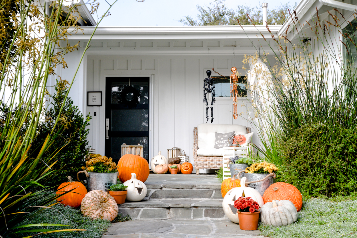 decorative pumpkins and mums and lanterns on a slate porch in a front yard