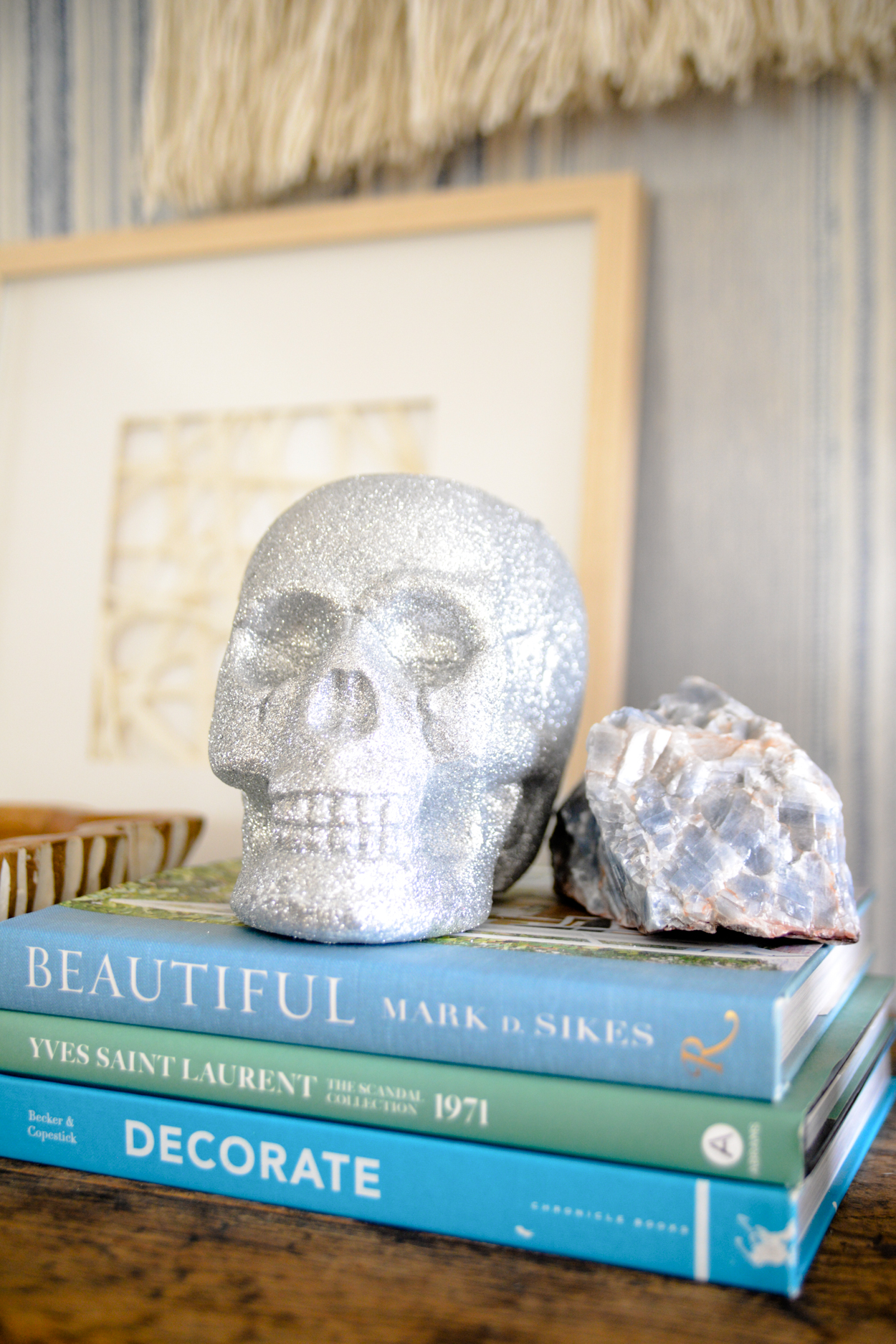 Silver glitter skull sitting on a stack of blue books