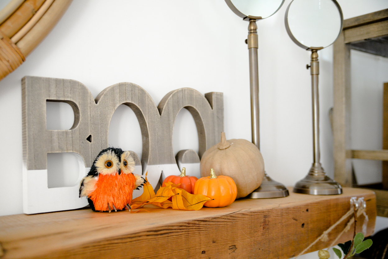 Wooden boo sign and paper pumpkin and orange owl sitting on a rustic wooden mantel 