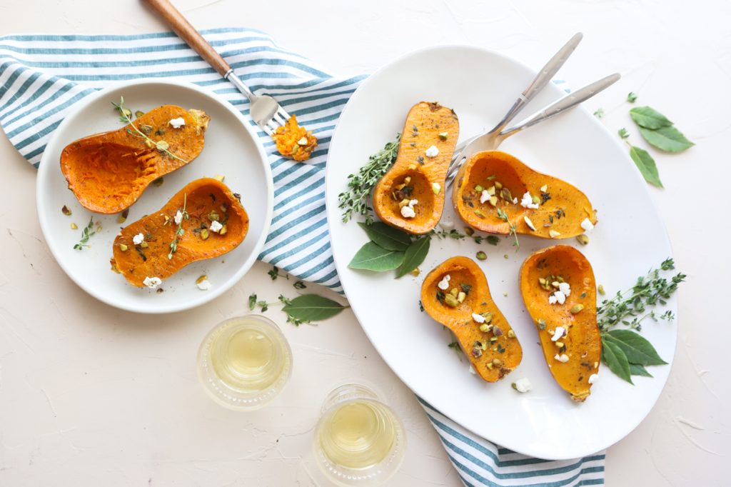 honeynut squash on a white plate sprinkled with goat cheese and pistachios