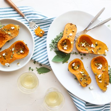 honeynut squash on a white plate sprinkled with goat cheese and pistachios