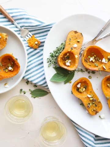 honeynut squash on a white plate sprinkled with goat cheese and pistachios