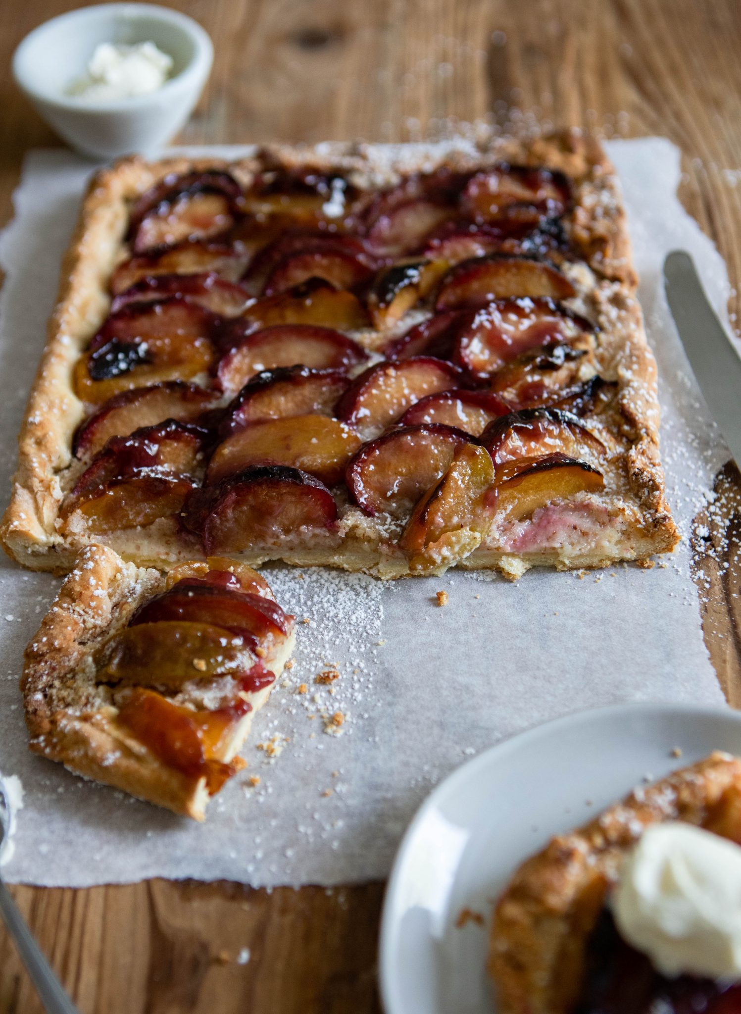 head on shot of a piece of rustic plum tart on a round white plate