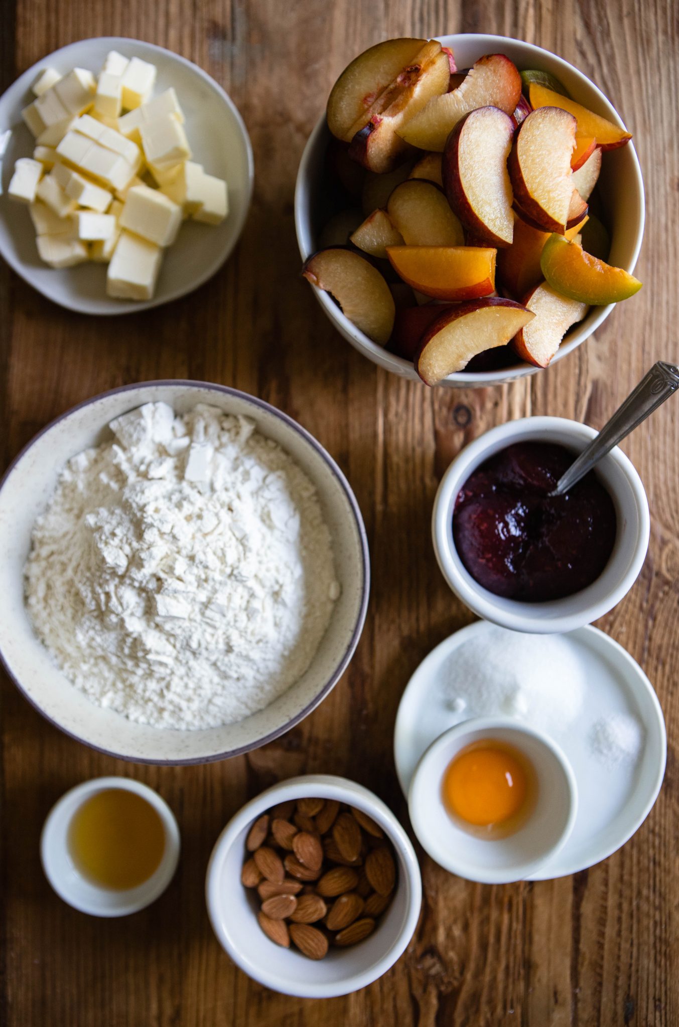 rustic plum tart ingredients on a wood surface