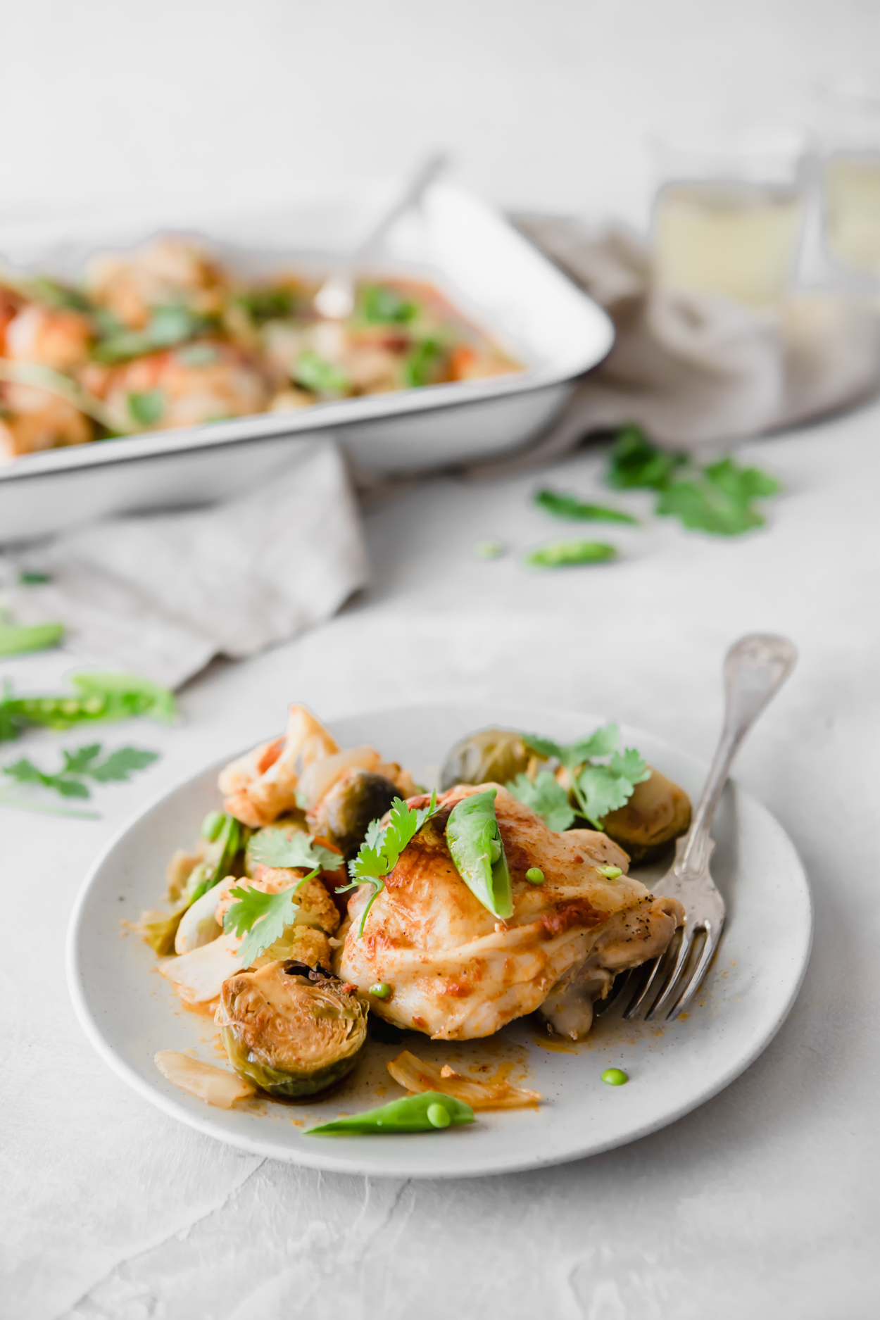 chicken and vegetables with red Thai curry sauce on a white plate