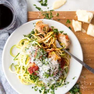 fork digging into a plate of healthy turkey meatballs set over zoodles and marinara sauce
