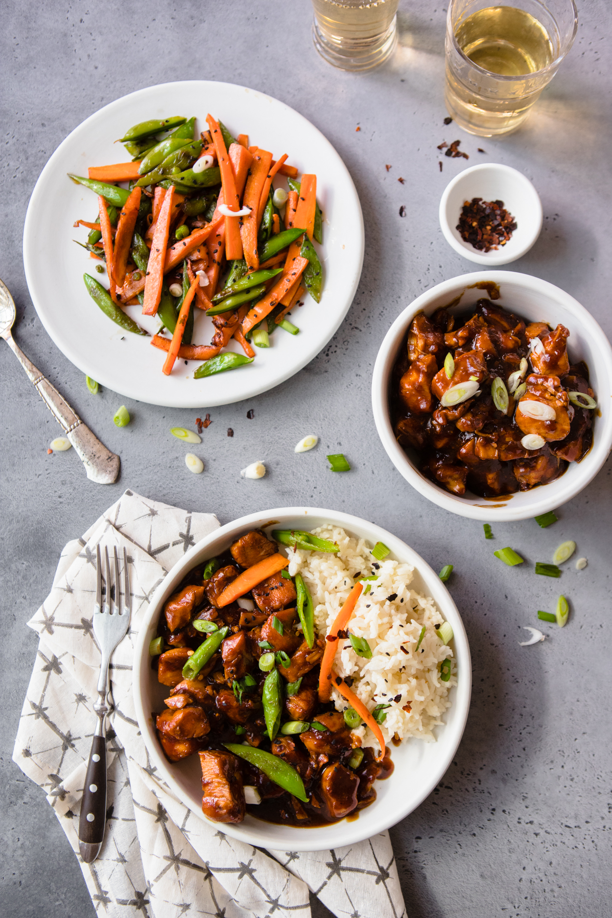  Instant Pot General Tso's Chicken in a white bowl with a side of carrots and snow peas, and a bowl of General Tso's Chicken and rice