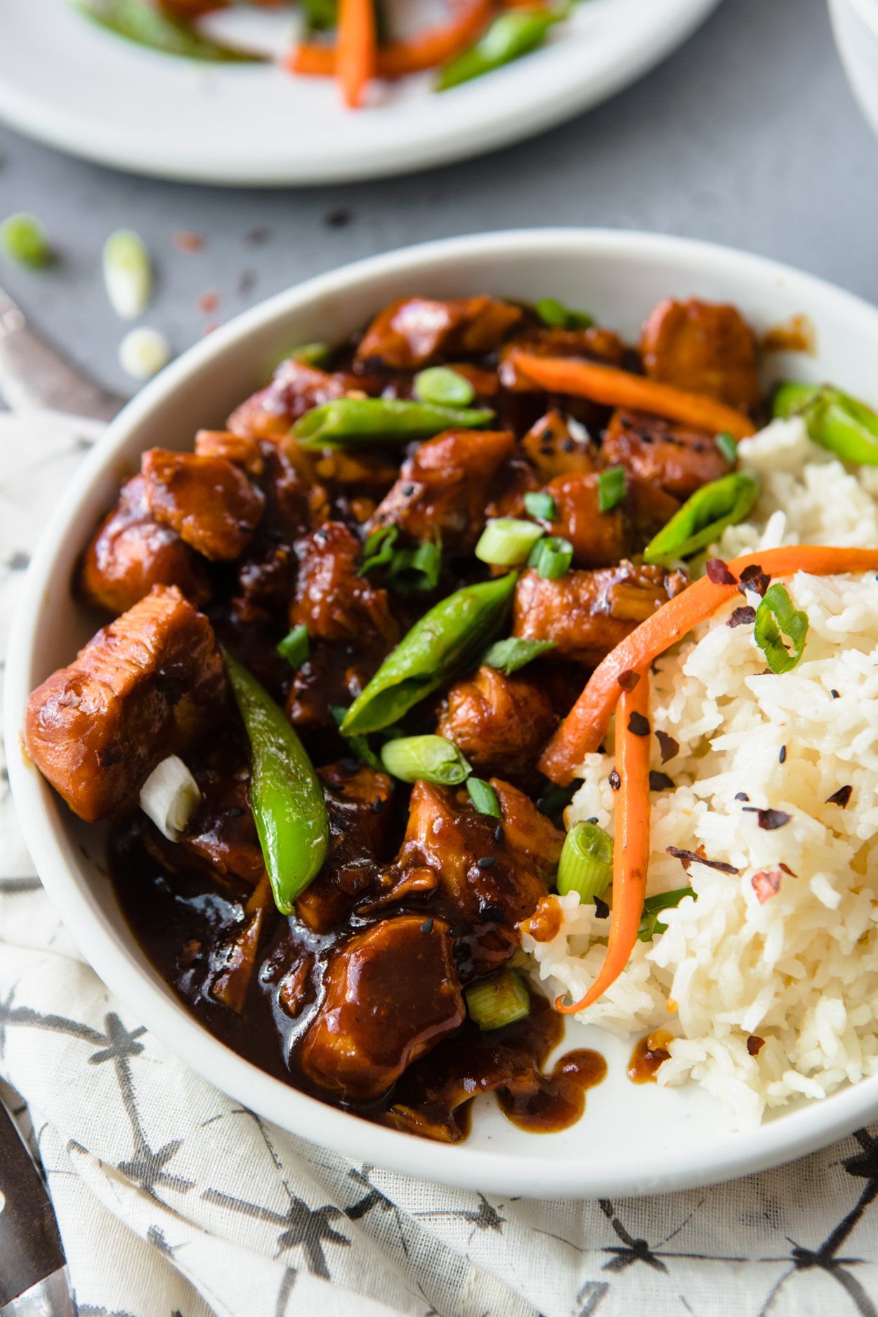 Instant Pot General Tso's Chicken garnished with carrots and greens, with white rice on the side