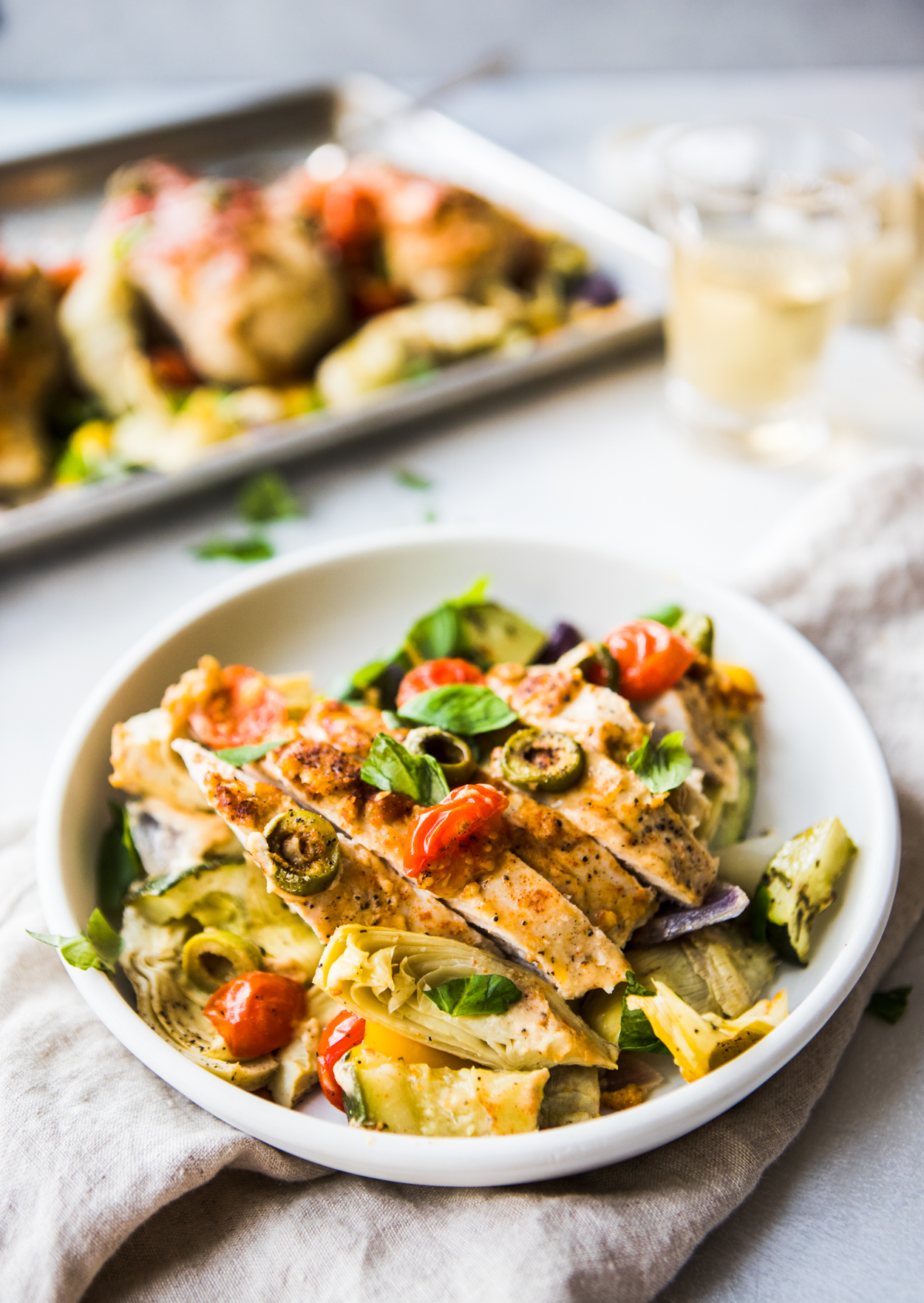 hummus chicken baked with vegetables on a white plate and beige napkin 