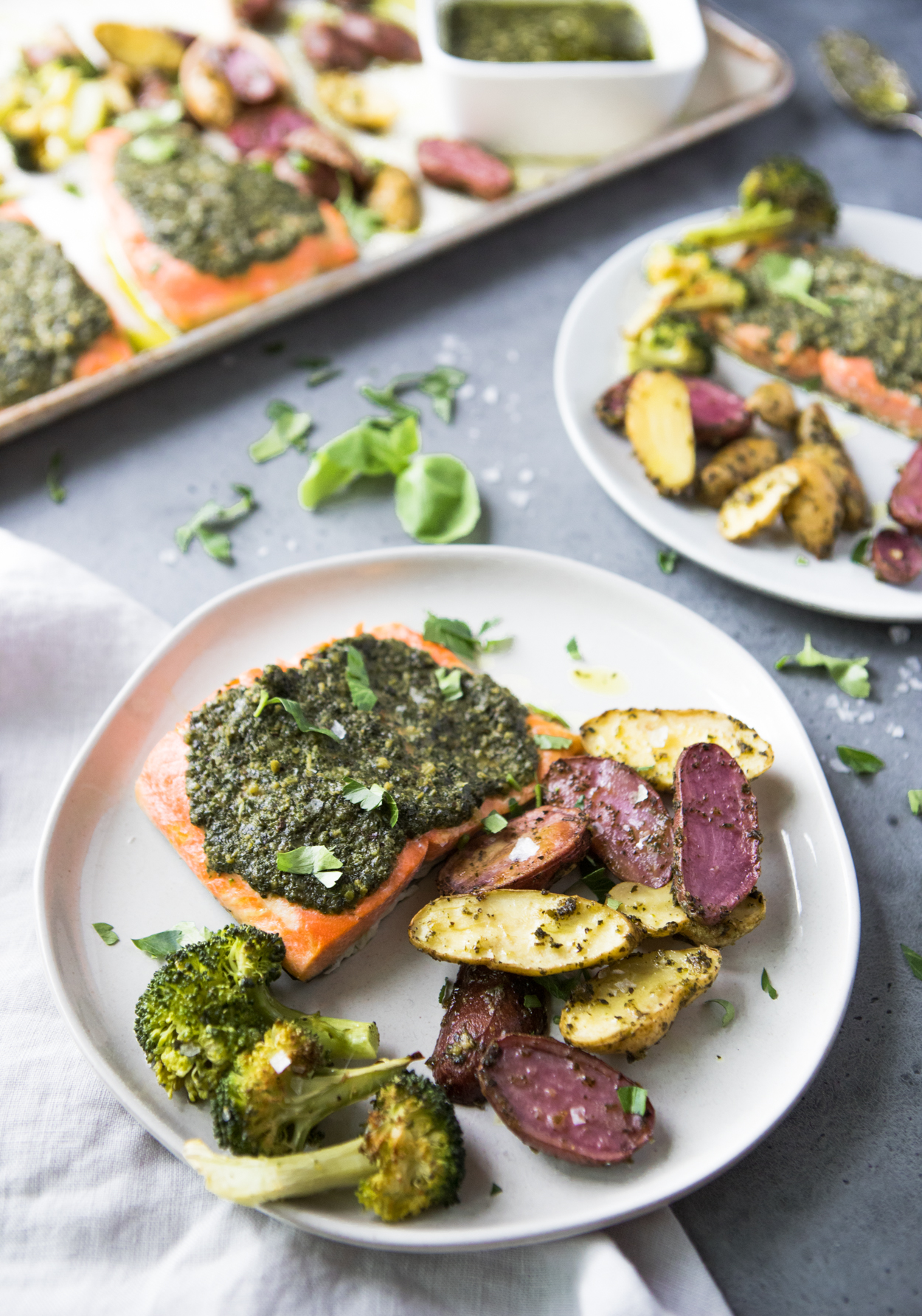 Baked salmon with pesto broccoli and potatoes on a white round plate