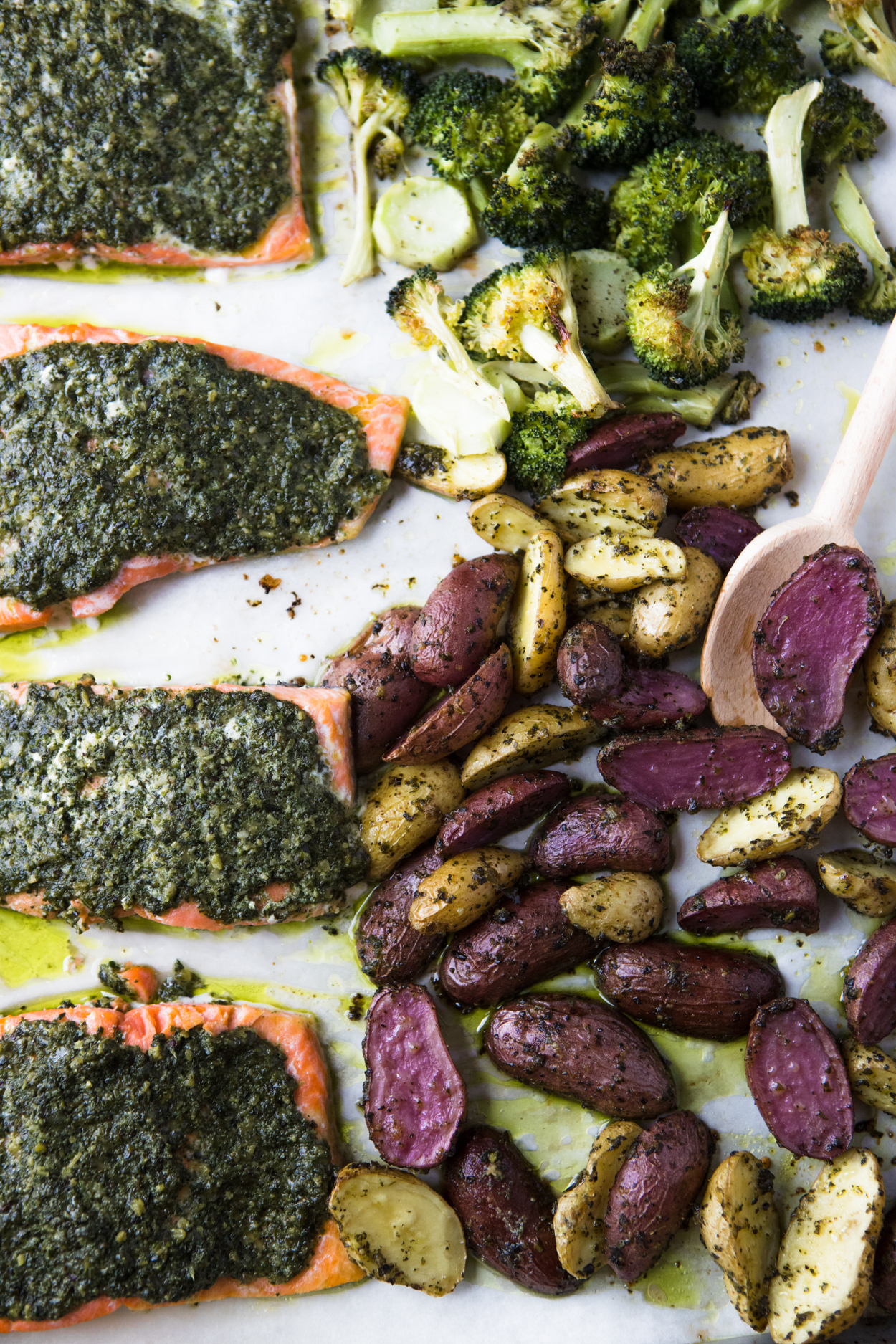 salmon with pesto and potatoes and broccoli on a baking sheet