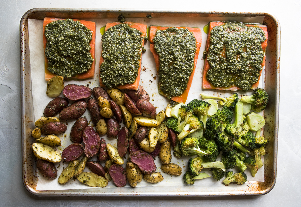 broccoli, potatoes, salmon and pesto on a baking sheet