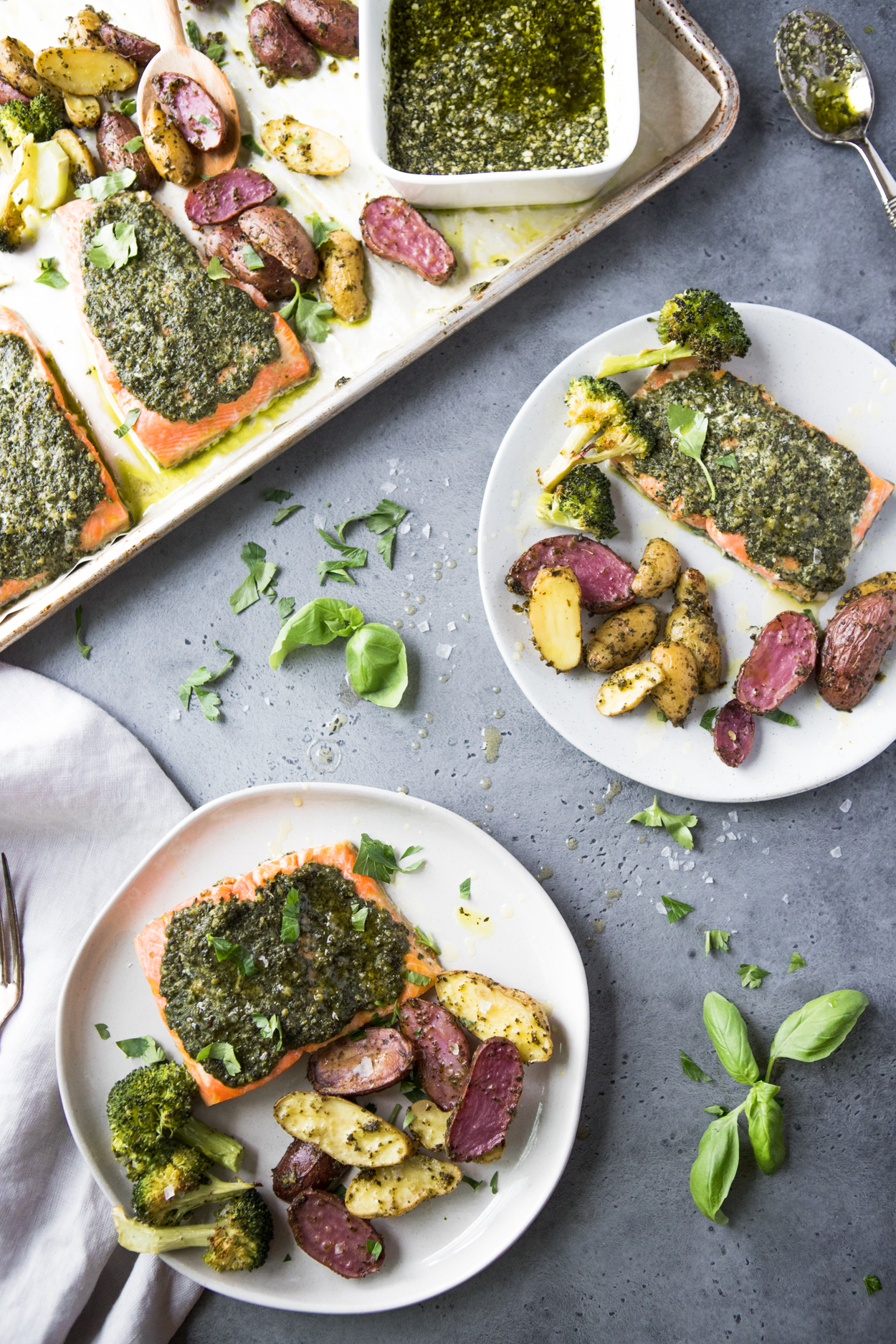 baked pesto Salmon with potatoes and broccoli on white plates