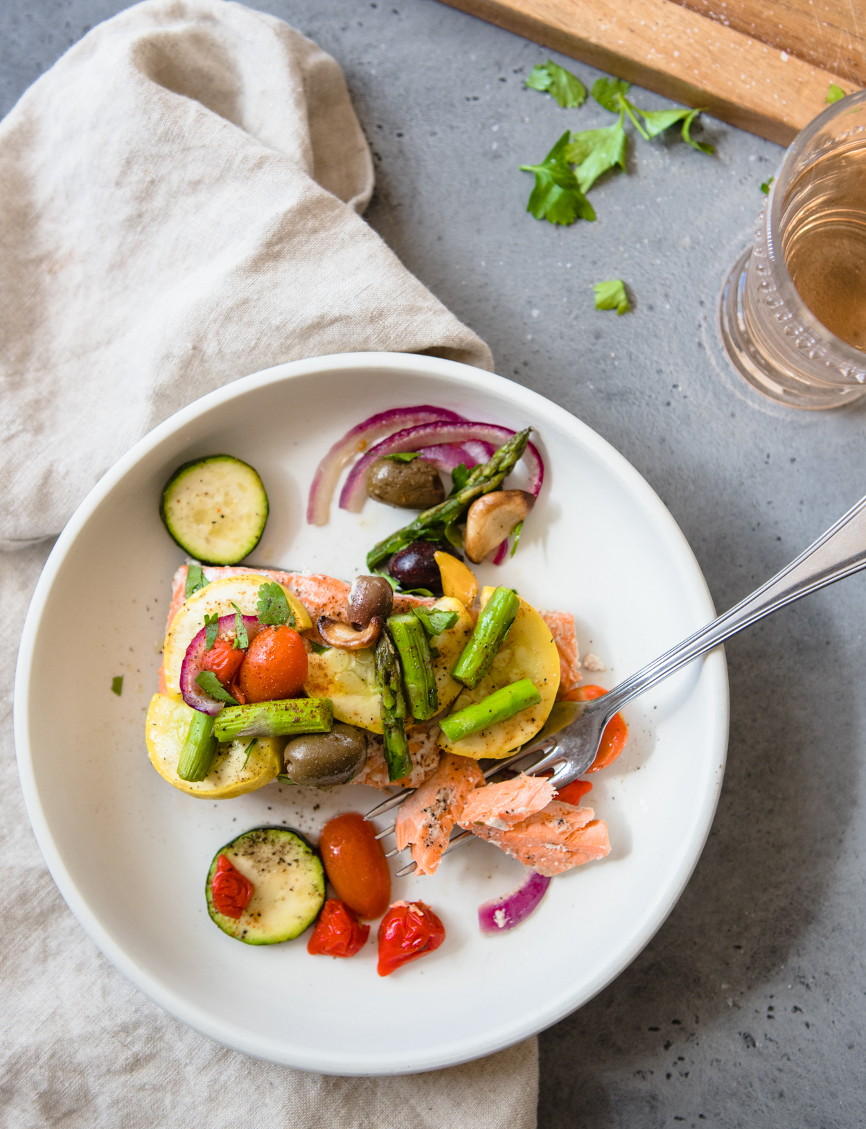 salmon with tomatoes, zucchini, asparagus, onions and olives on a white plate