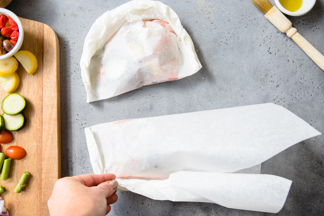 salmon and veggies being folded in parchment paper 